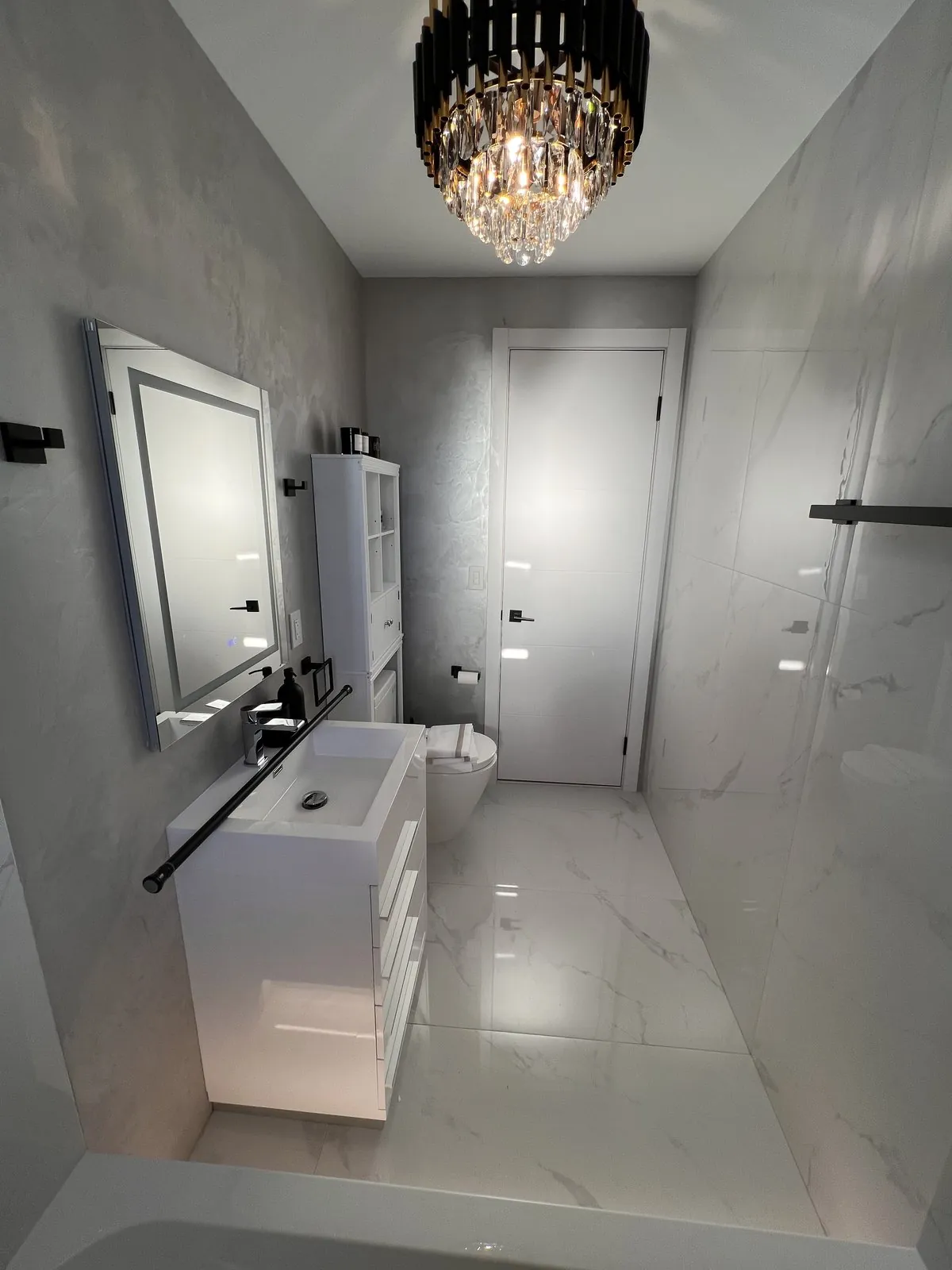 Finished marble bathroom with chandelier and floating vanity
