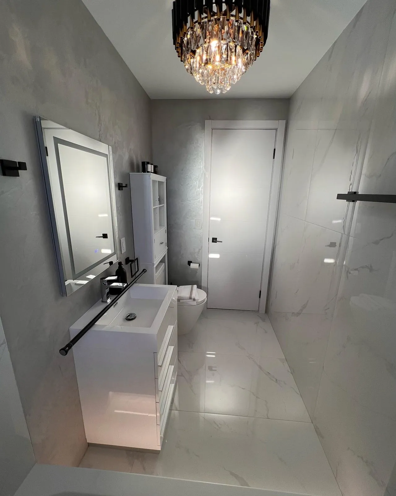 White marble bathroom with crystal chandelier and floating vanity