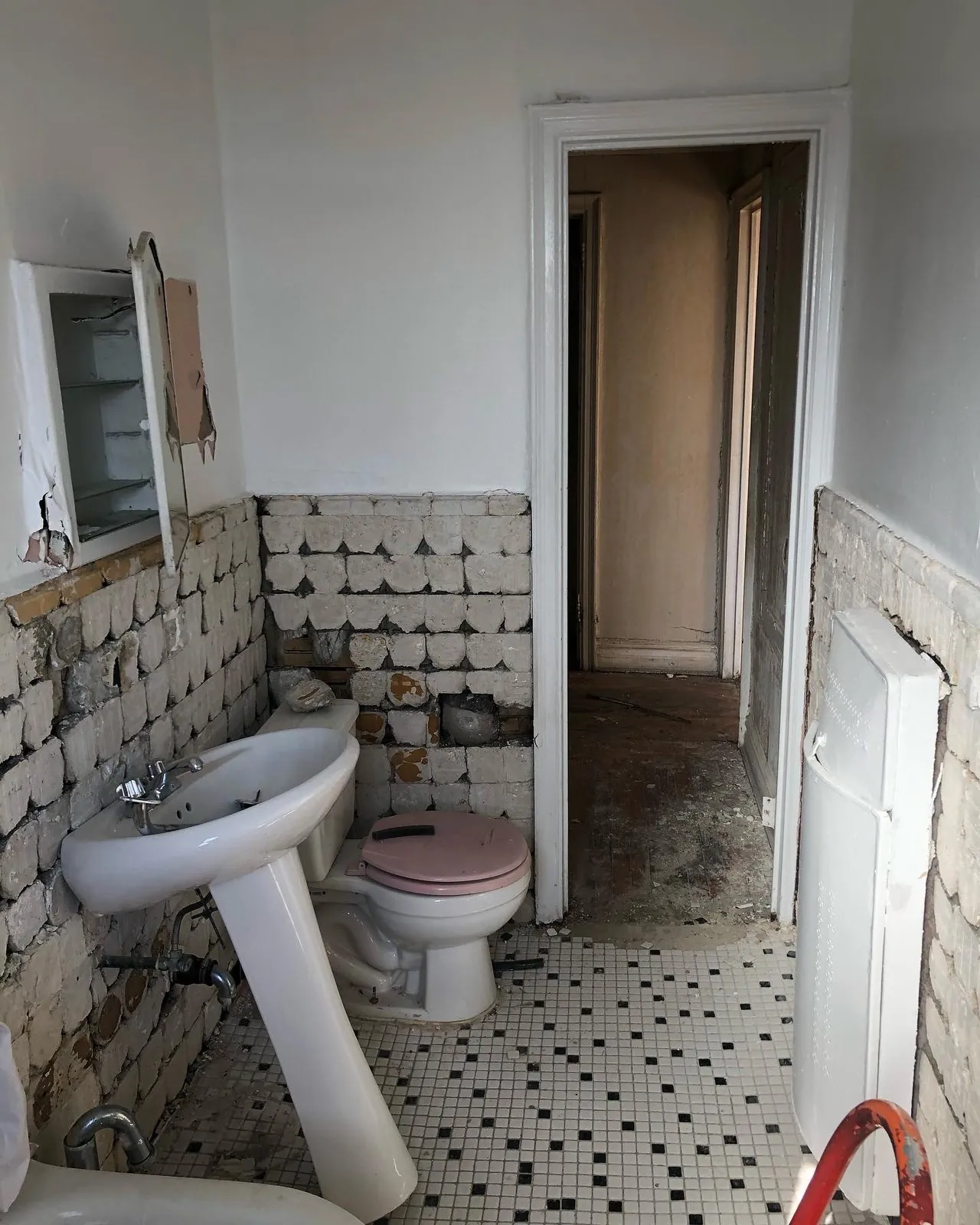 Old corridor bathroom with pedestal sink and mosaic floor