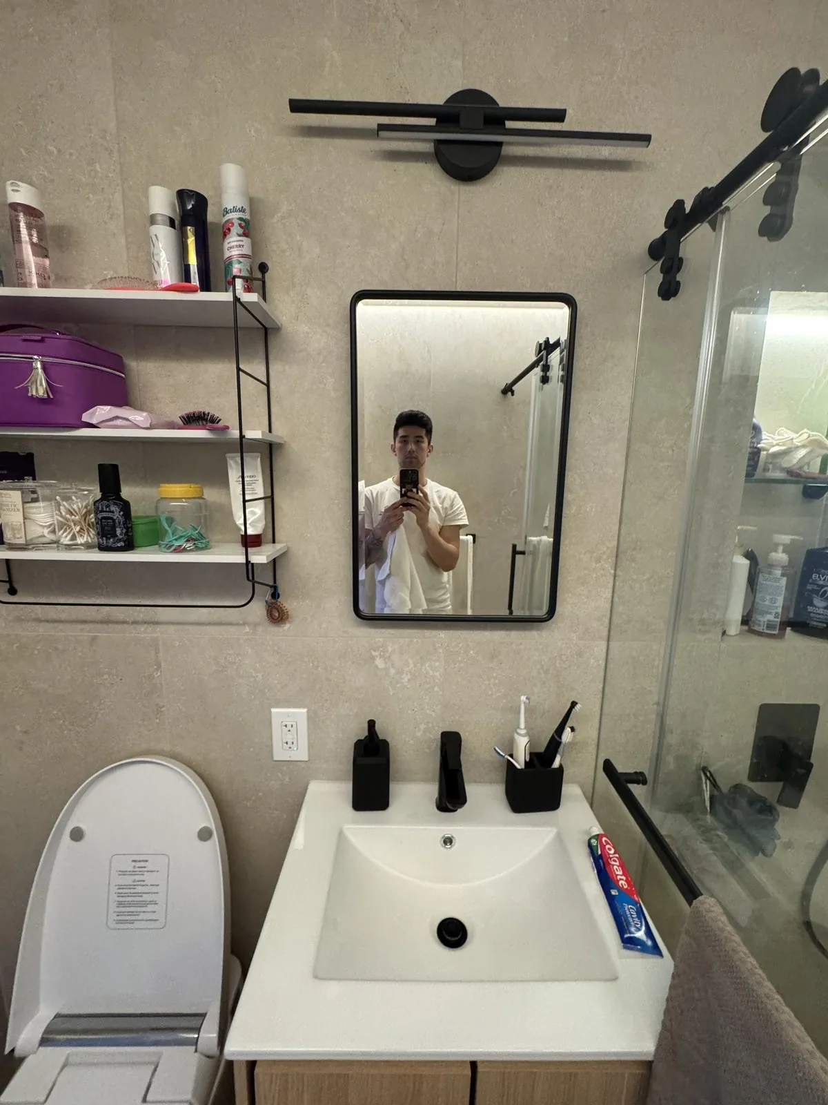 New wood vanity, white sink and black-framed mirror