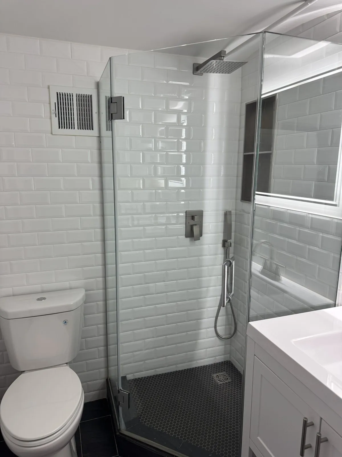Subway-tile walk-in shower with rain head and black penny floor