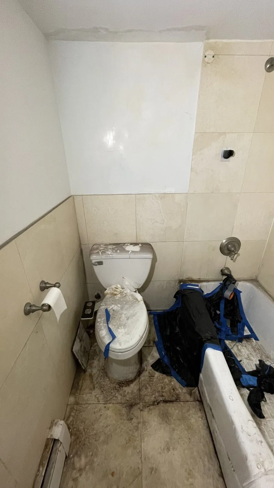 Dated beige-tile bathroom with an old tub before the rebuild