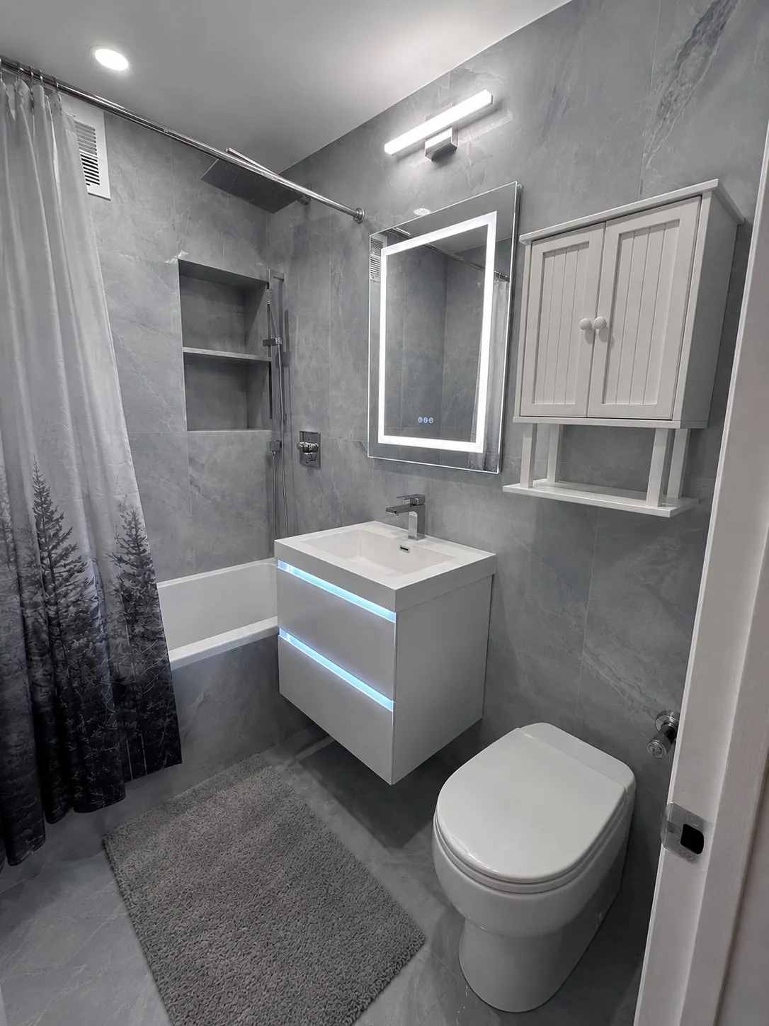 Gray marble bathroom with floating LED vanity and backlit mirror