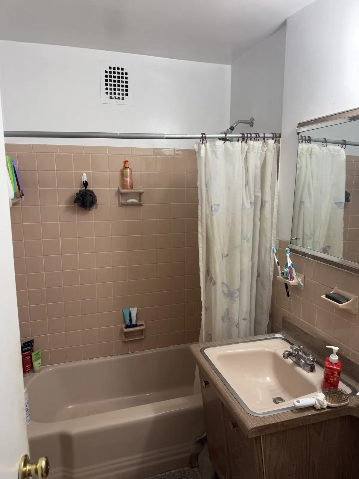 Old mauve-tile bathroom with dated tub and laminate vanity
