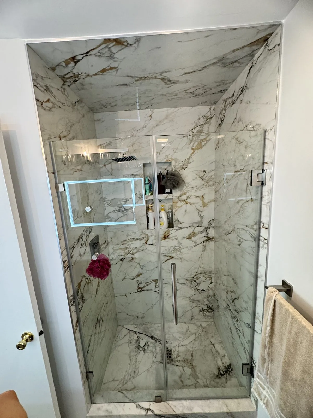 Frameless glass walk-in shower in book-matched Calacatta marble
