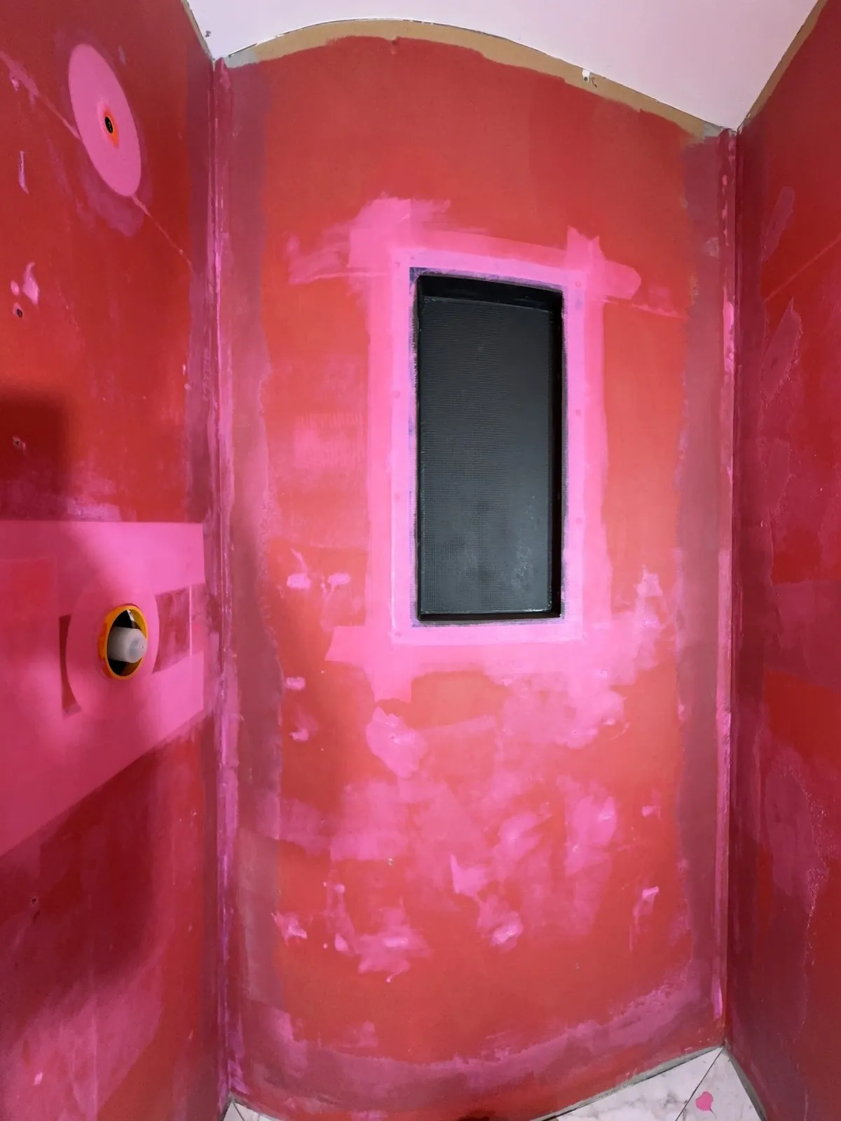 Red waterproofing membrane over the walls with the niche cut in
