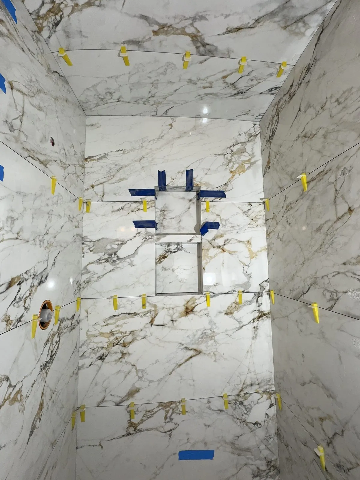 Calacatta marble walls set with leveling clips, the niche framed