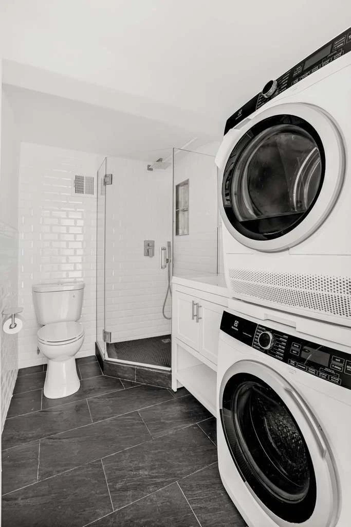 Rebuilt bathroom with stacked washer/dryer and glass shower