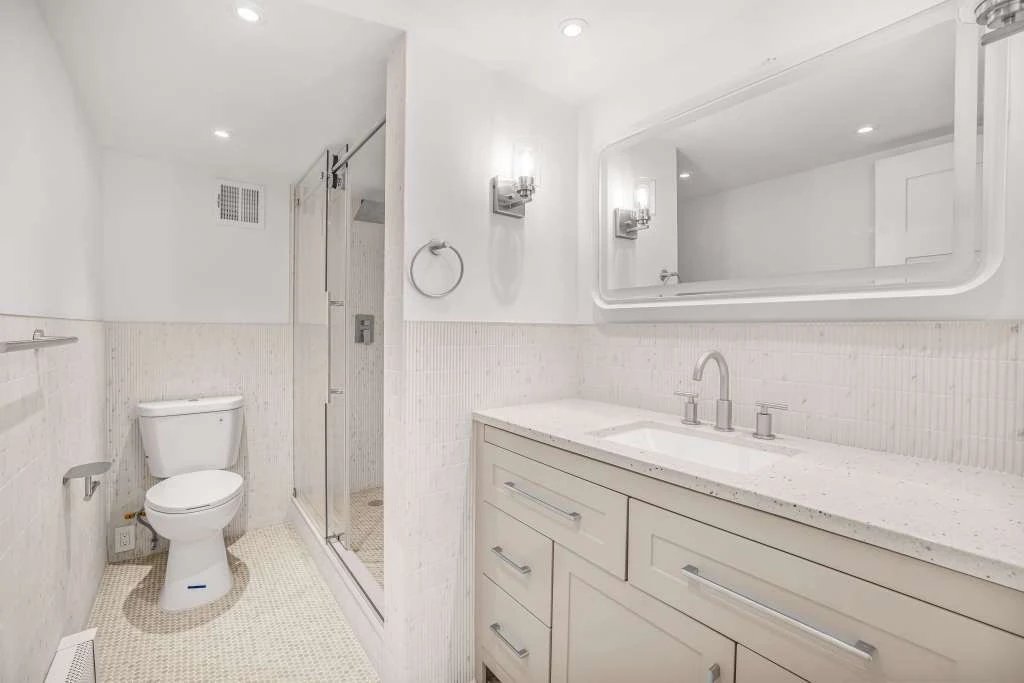 Finished Manhattan condo bathroom — walk-in glass shower, vanity and mirror